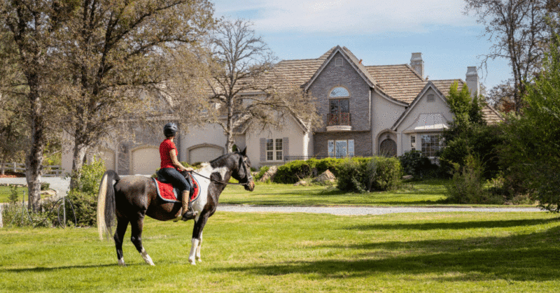 Equestrian rider on front lawn of luxury home